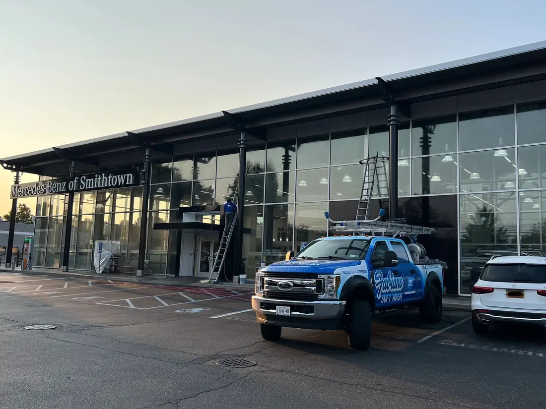 Fabian’s Soft Wash truck and ladders at a glass-front car dealership