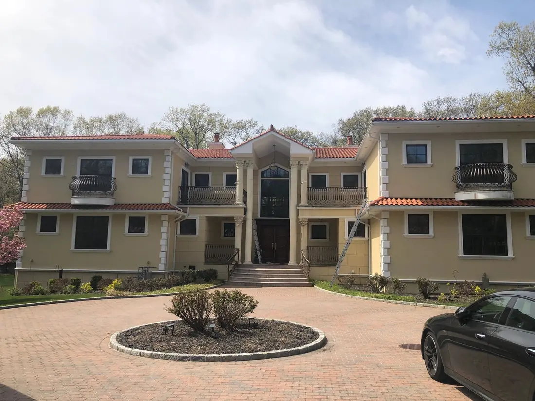 Clean brick paver driveway in front of a large Long Island home